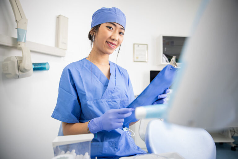 Dentist in blue scrubs holding tools.