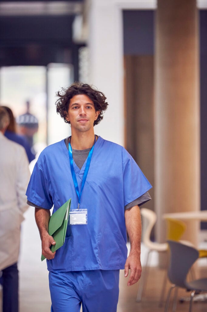 Doctor in scrubs walking confidently.