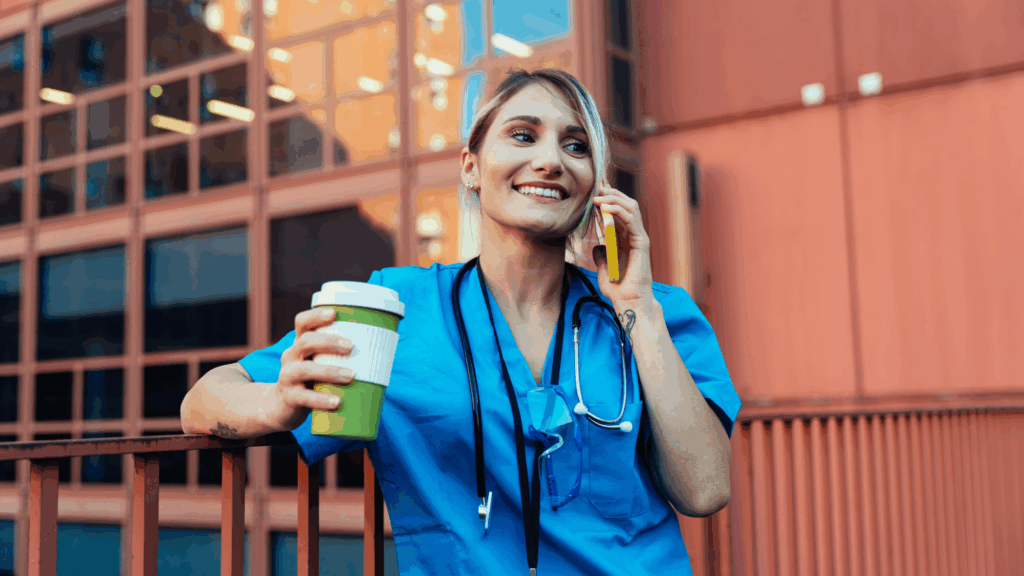 Female nurse enjoying a quick break outside holding coffee and talking on the phone