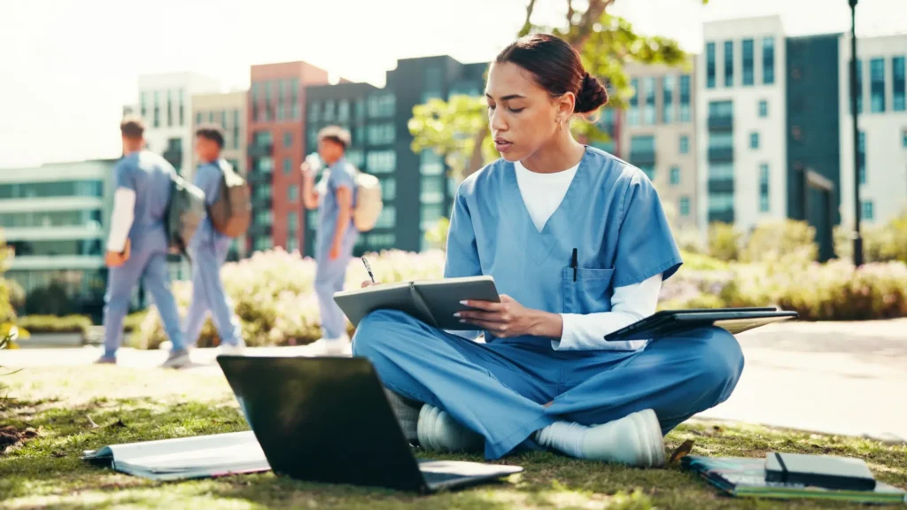 Seated female nurse studying in a park.