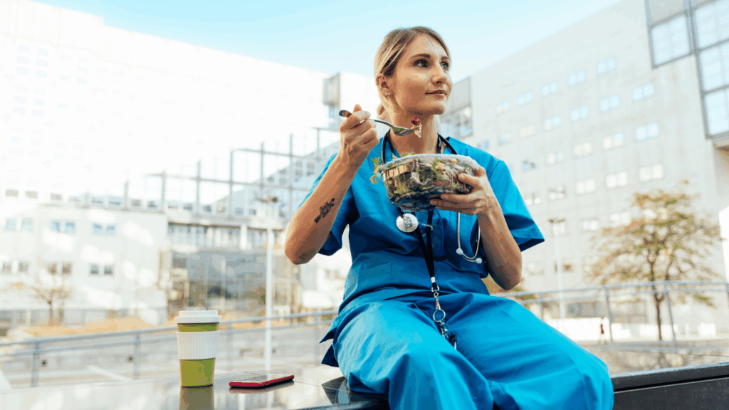 Female nurse on break eating a salad outside during a clear beautiful day.
