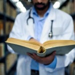 Doctor reading book in library