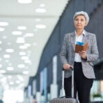 Elderly traveler with suitcase and passport.